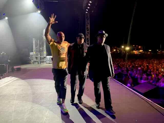 Performers walking onstage to greet a nighttime festival crowd
