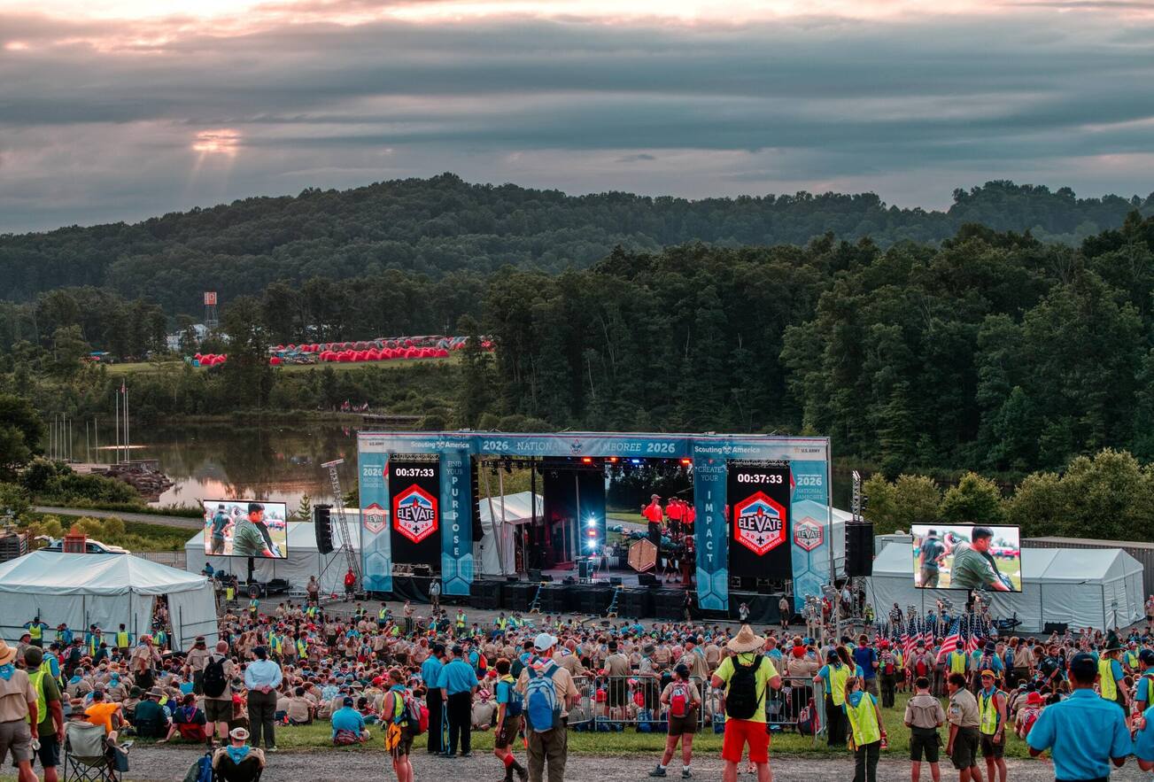 PM1 main stage and crowd of scouts at the 2026 Scouting America National Jamboree, with forest and lake behind