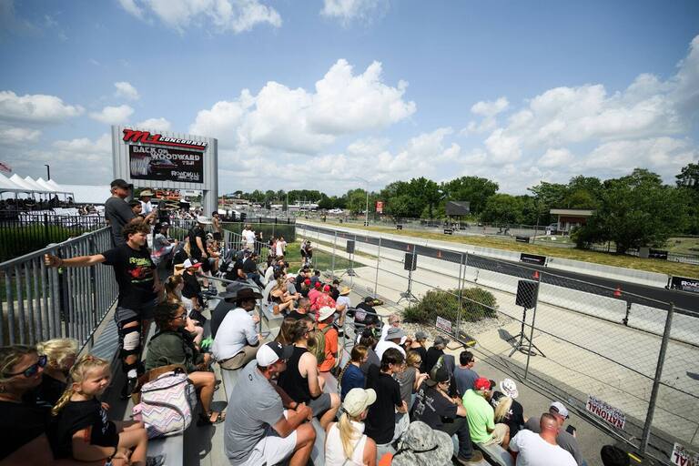 Spectators seated in a PM1 grandstand along the track on Woodward Avenue