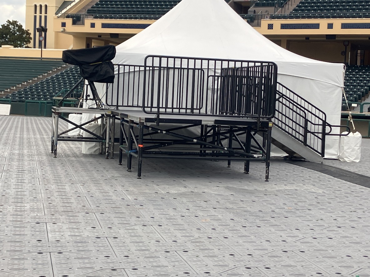 Camera platform with railing and stairs on field protection flooring inside a stadium
