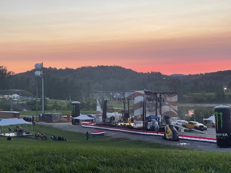 Outdoor PM1 stage with a full American flag backdrop at dusk