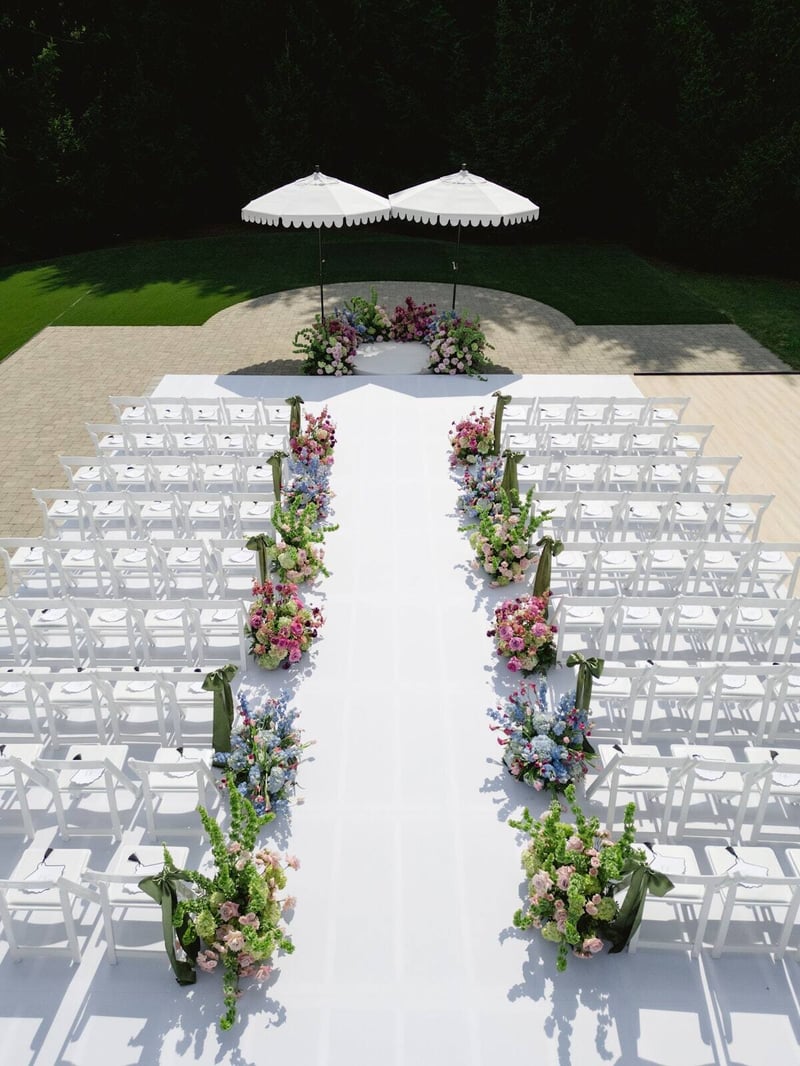 Wedding ceremony set on a white PM1 platform with rows of white chairs and a floral aisle