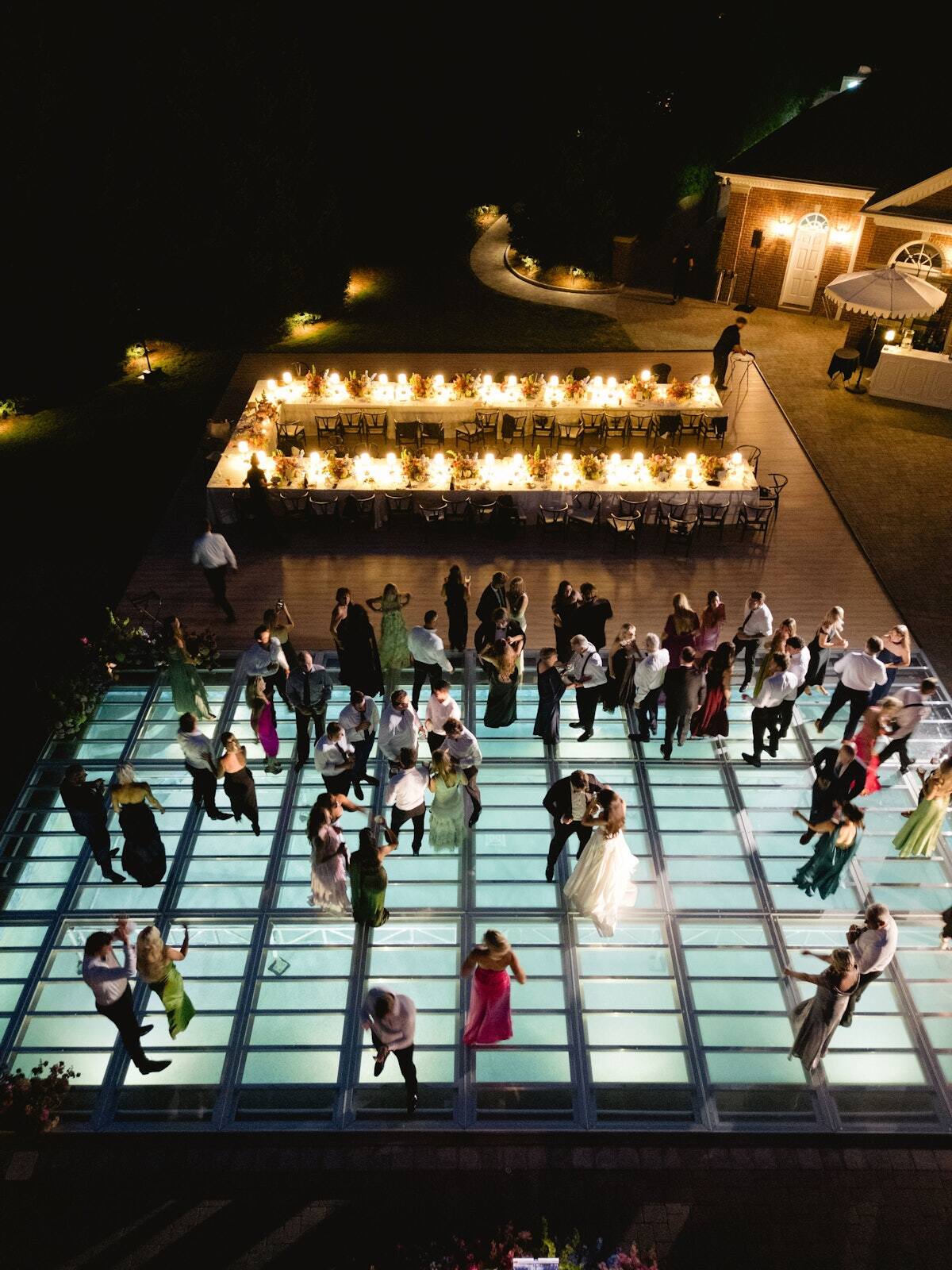 Guests dancing at night on a clear PM1 pool cover dance floor at a Detroit-area estate