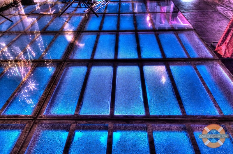 Illuminated pool cover dance floor with a grid of blue-lit squares at night
